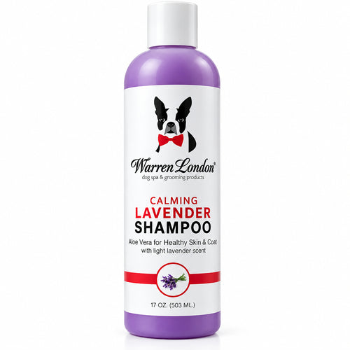 A bottle of Warren London Calming Lavender Shampoo stands next to a small light-colored dog on a plain white background. The bottle is lavender purple with a white cap and a white label featuring a black-and-white dog graphic and red text.