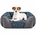 A small white and tan dog lies on a plush gray pet bed with a textured blue-gray sherpa-style lining, photographed against a clean white background.