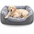 A golden retriever puppy lying inside a plush gray dog bed on a clean white background.